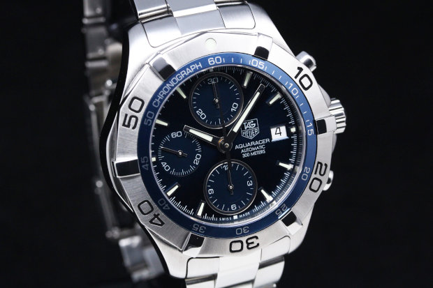 Blue dial with luminous silver-tone hands and stick hour markers. Minute markers around the outer rim. 